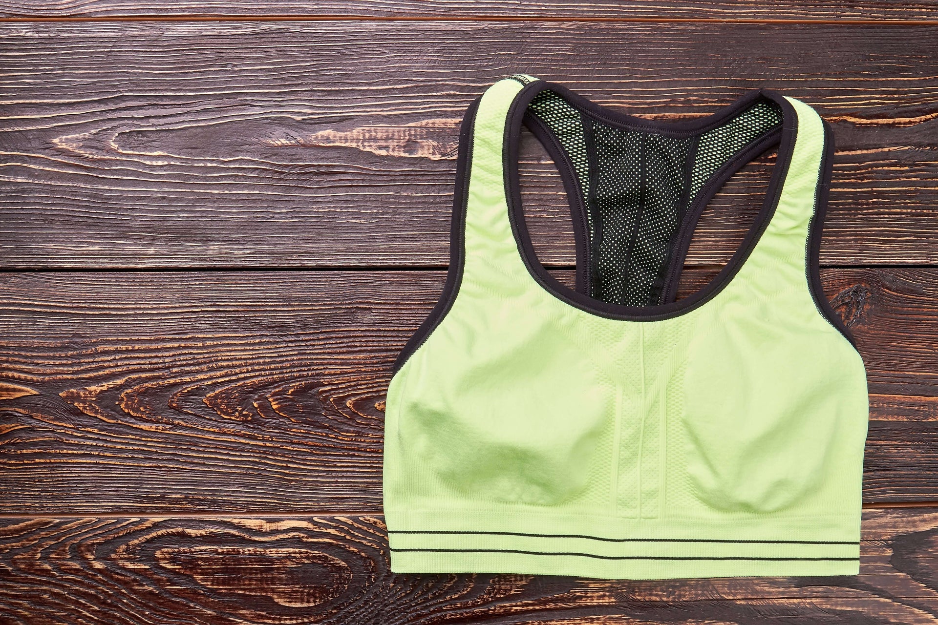 How Often Should I Replace My Sports Bra: light green sports bra on a wooden background.